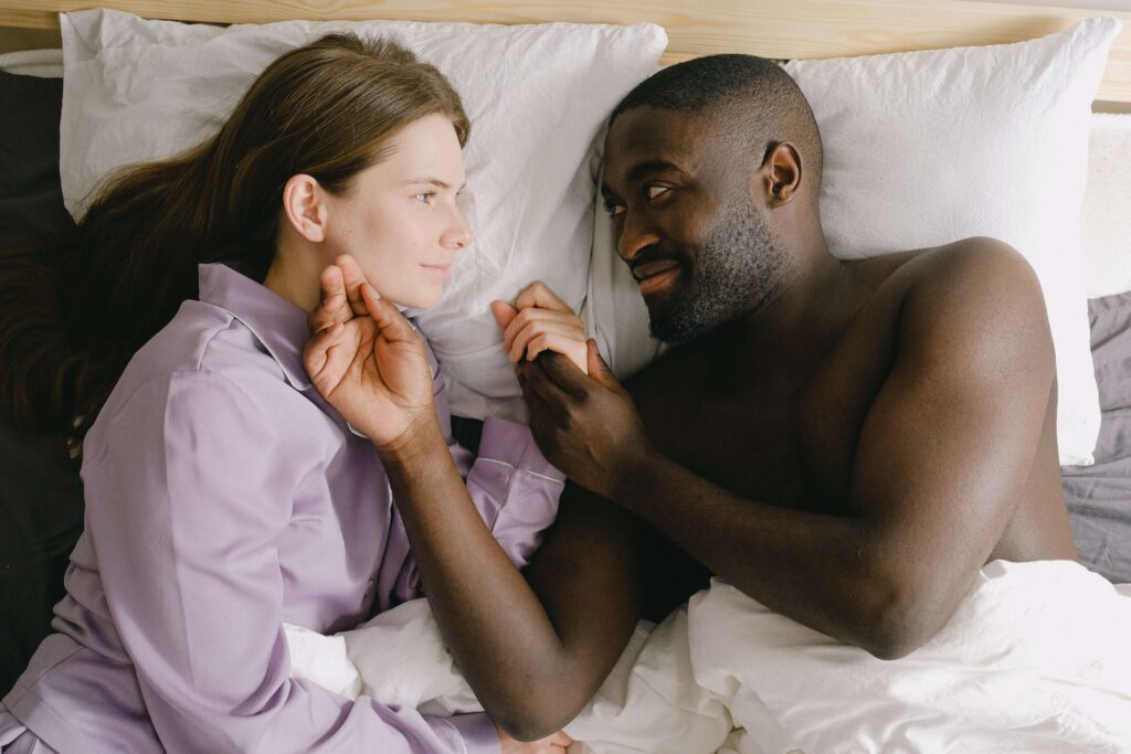 A man caressing his female partner's face in bed
